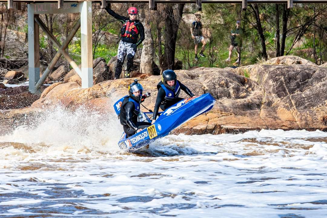 The 007 boat launching over a wave below a bridge on the Avon River