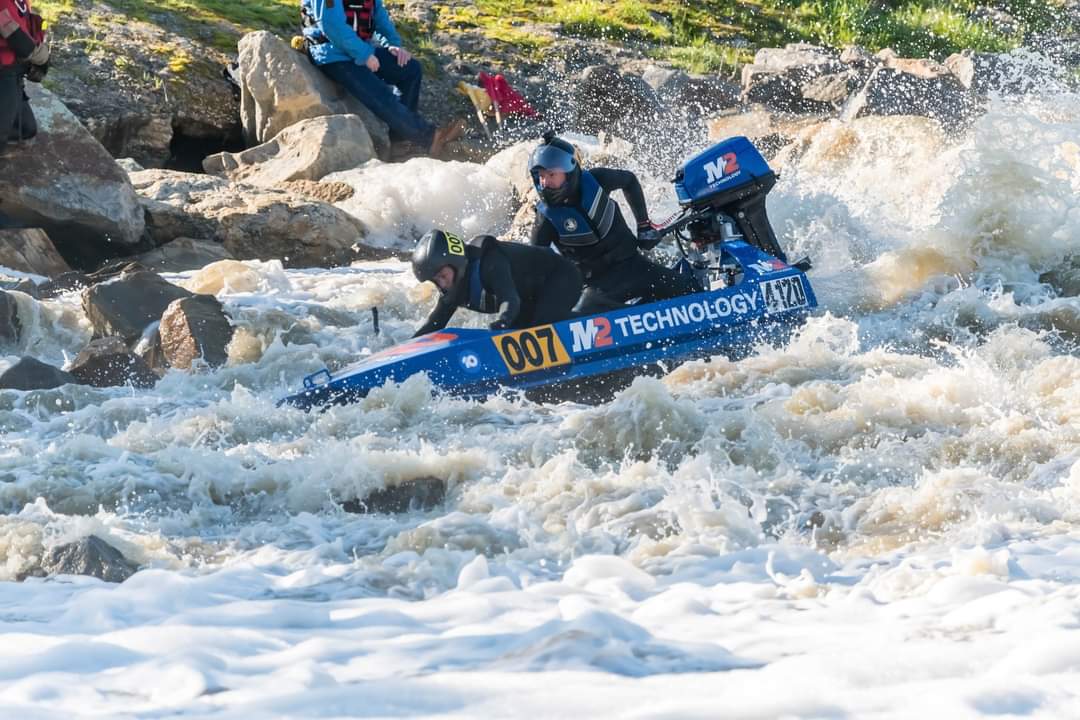 The M2 Technology 007 power dinghy driving through white water past spectators on the rocks