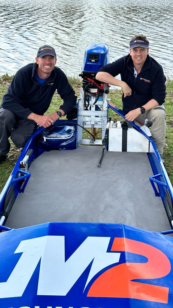 Two team members with the 007 power dinghy at the riverbank